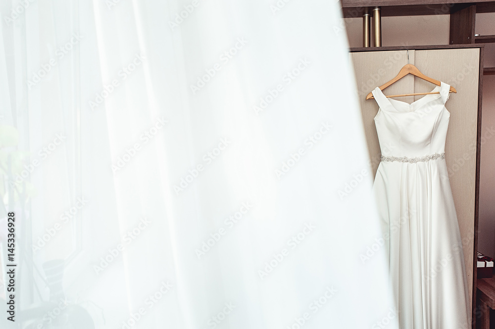 Simple white wedding dress on the rack at the wardrobe