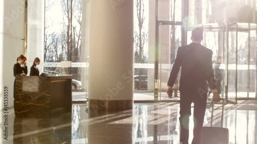 Young neat man leaving hotel in sunlight