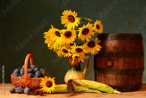 Fototapeta Naklejka Na Ścianę i Meble -  Wooden barrel, sunflowers in a vase and plum on the table