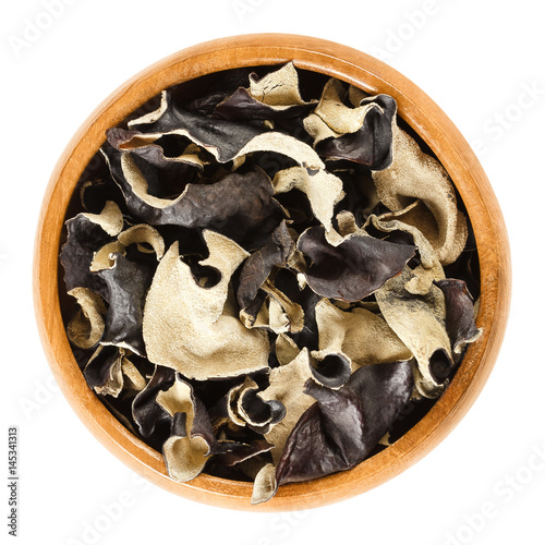 Dried black fungus in wooden bowl. Auricularia auricula-judae, also known as Jew's, wood or jelly ear, or Mu Err. Ingredient in Chinese dishes. Macro food photo close up from above on white background photo