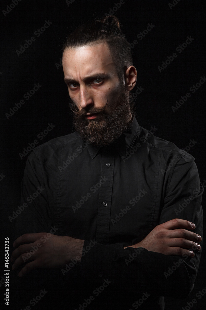 Studio portrait of a handsome man with a beard in the black shirt