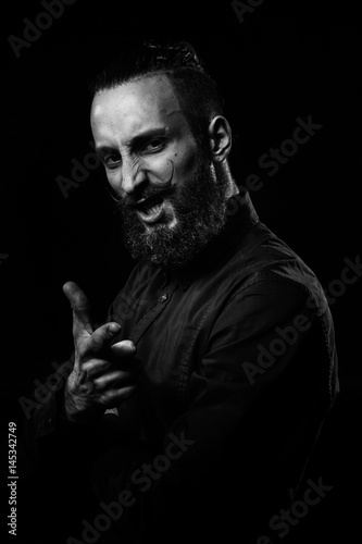 Black and white studio portrait of a handsome man with a beard in the black shirt