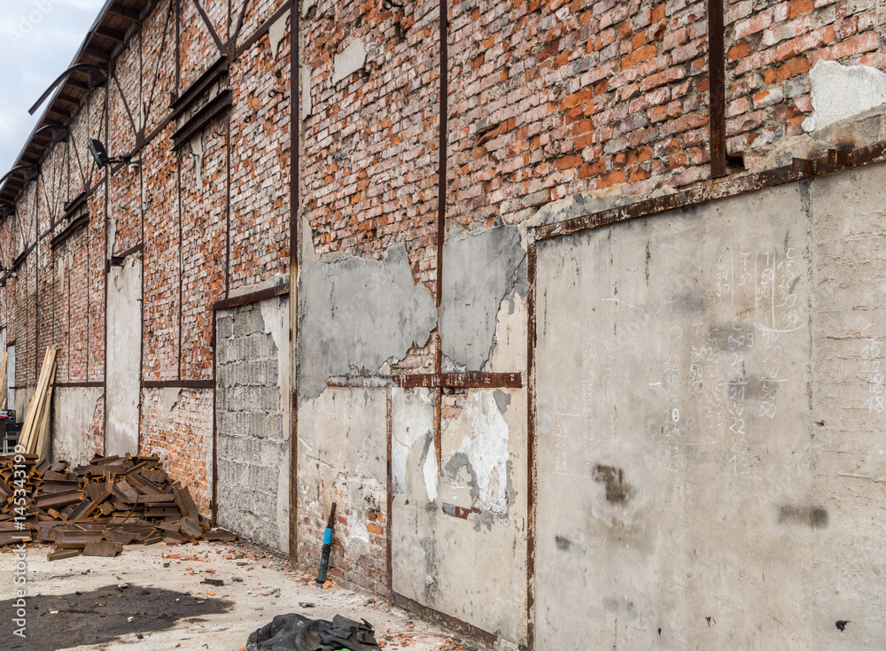 Abandoned factory ruins outside view on old brick wall with walled doors and entry gates