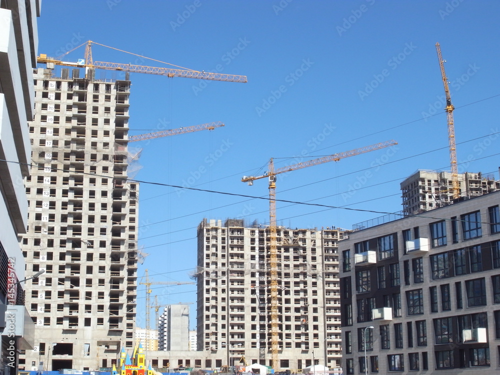 Construction of a house in the city. Building construction process, building tower cranes against sky background.