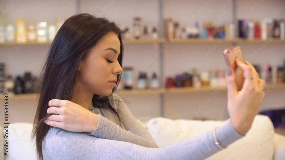 Young beautiful girl taking pictures of herself in the Studio makeup. She sits on the couch