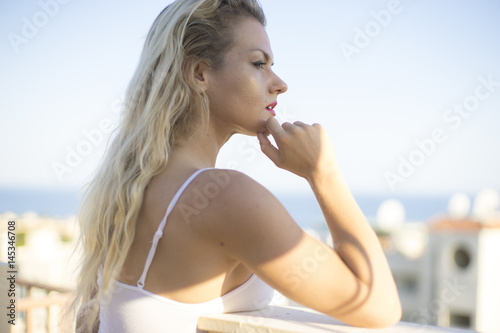 Blond girl with light clothing in white color next to mediterranean sea in the city of Marbella, spain