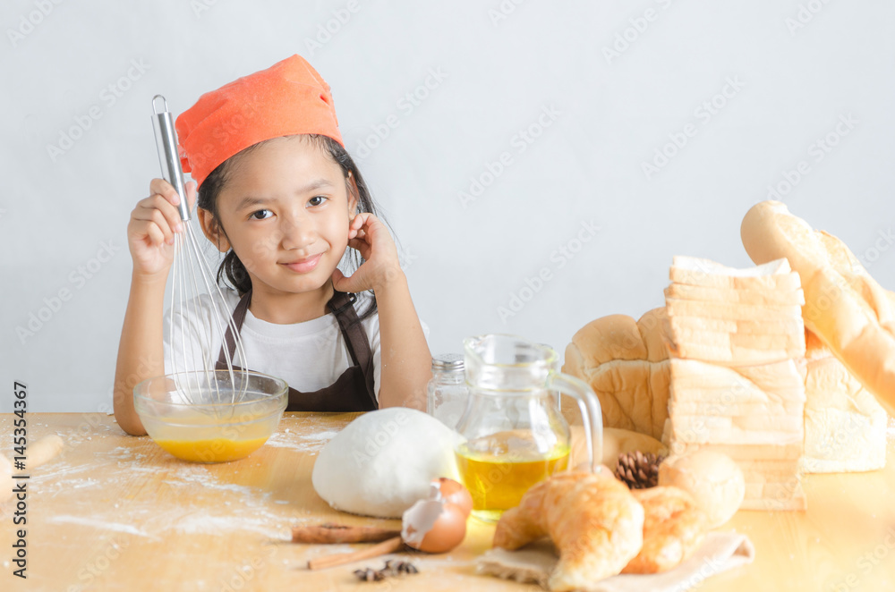 Asian little girl using stainless steel whisk to mix the egg for making bakery Asian little girl using stainless steel whisk to mix the egg for making bakery