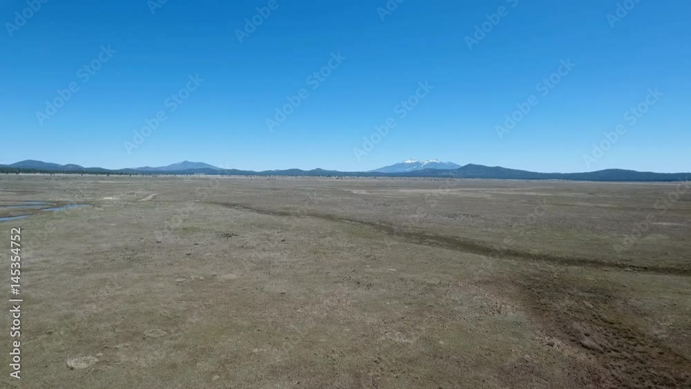 Aerial view of a vast prairie with snow capped mountains in the distance Aerial view of a vast prairie with snow capped mountains in the distance