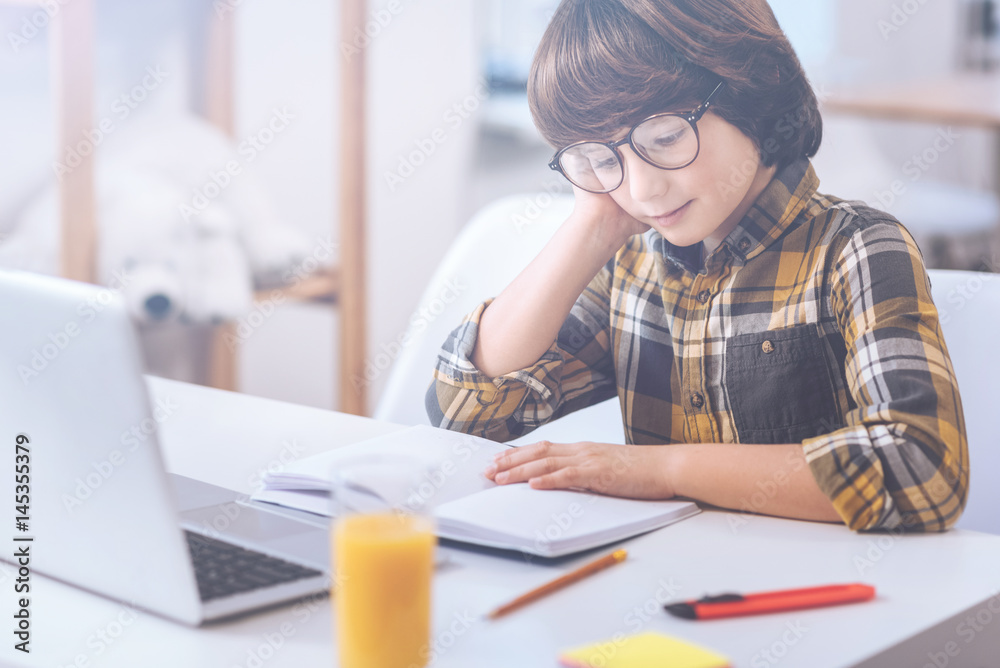 Contemplative boy looking at exercise book