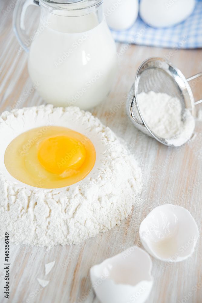 Ingredients and tools for baking - flour, eggs and glass of milk on the wooden rustic table background, selective focus Ingredients and tools for baking - flour, eggs and glass of milk on the wooden rustic table background, selective focus