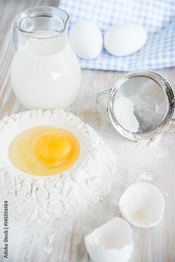 Ingredients and tools for baking - flour, eggs and glass of milk on the wooden rustic table background, selective focus Ingredients and tools for baking - flour, eggs and glass of milk on the wooden rustic table background, selective focus