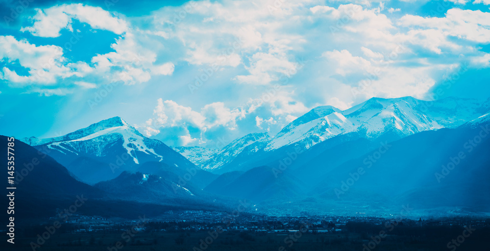 Photo depicting a beautiful moody frosty landscape. European alpine mountains with snow peaks on a blue sky background.
