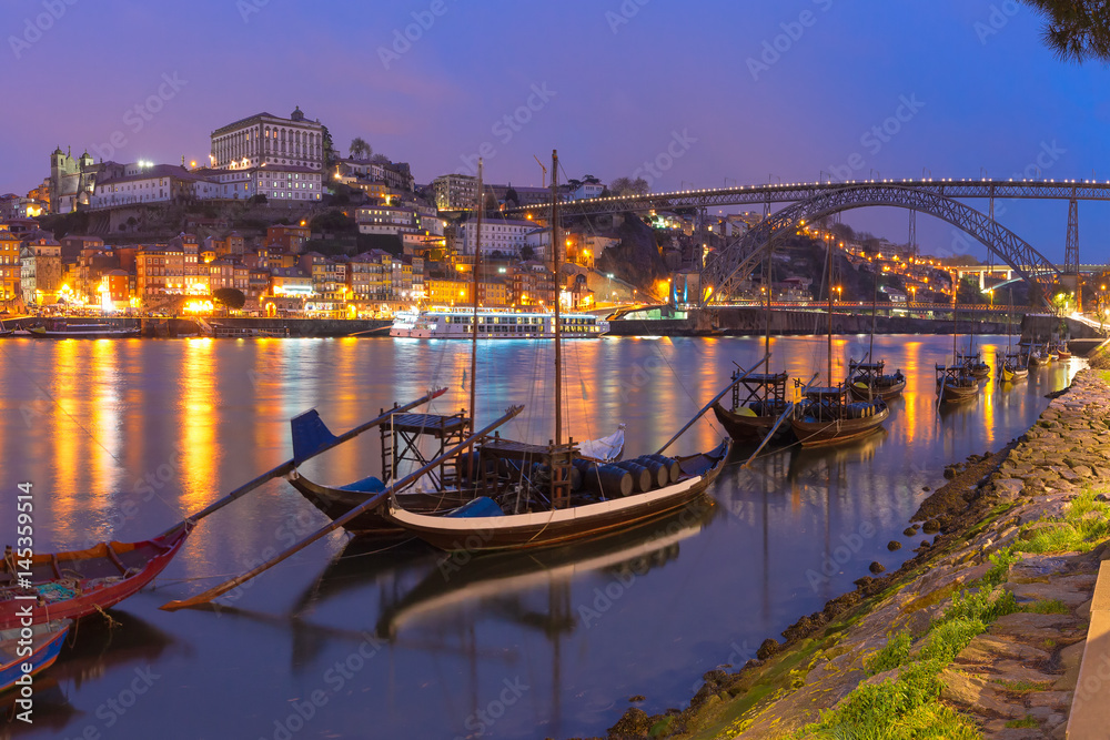 Traditional rabelo boats with barrels of Port wine on the Douro river, Ribeira and Dom Luis I or Luiz I iron bridge on the background, Porto, Portugal.