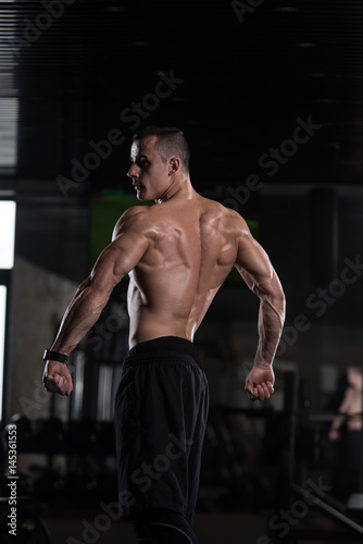 Muscular Man Flexing Muscles In Gym