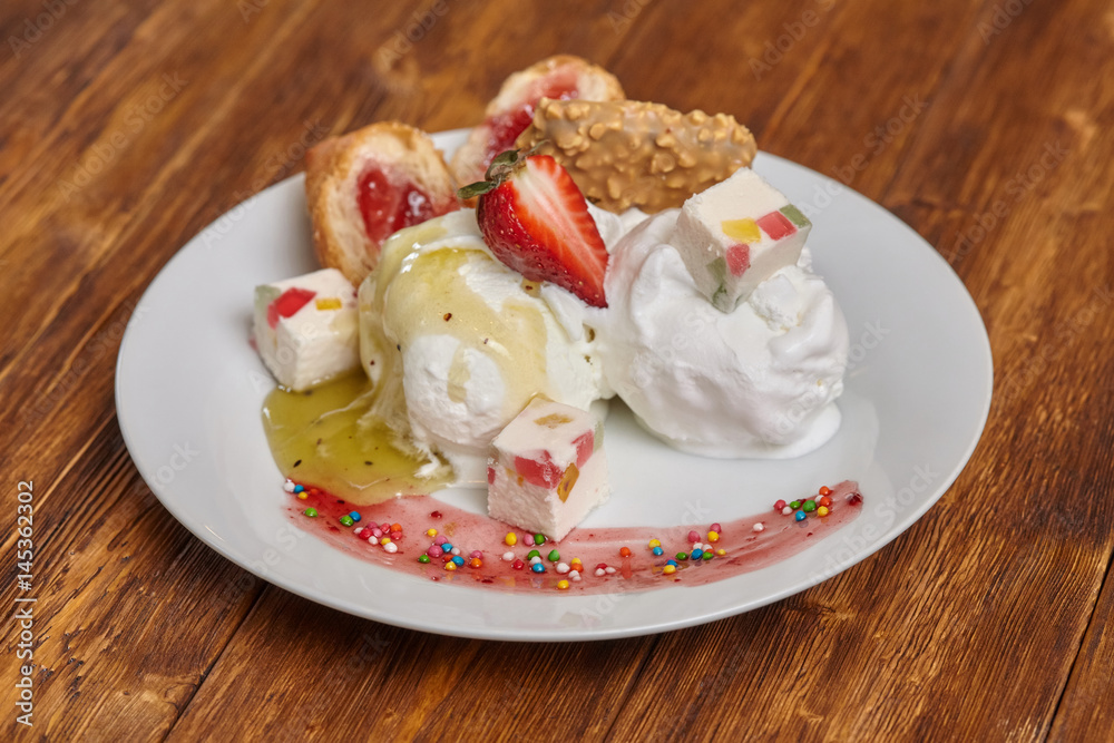 Ice cream on plate with strawberry, syrup and other treats Ice cream on plate with strawberry, syrup and other treats