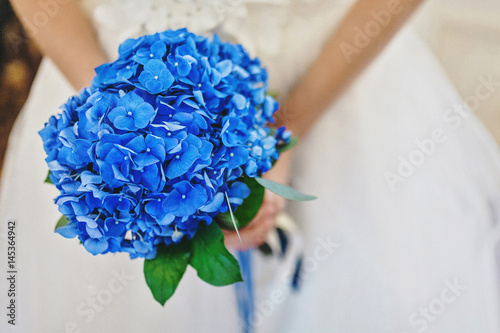 Blue wedding bouquet in the hands of the bride photo