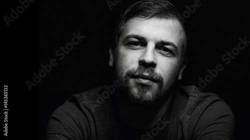young man close up portrait, on black background