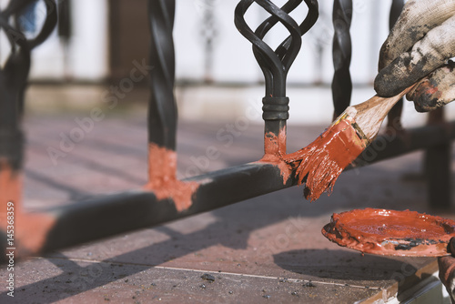 Painting forged railings on the stairs at the entrance of the house. Protection against rust. photo