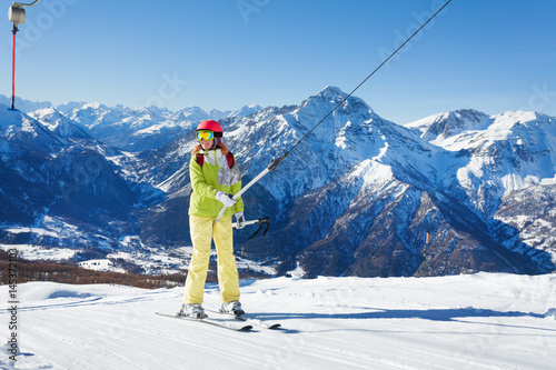 Happy young woman on button ski lift going uphill