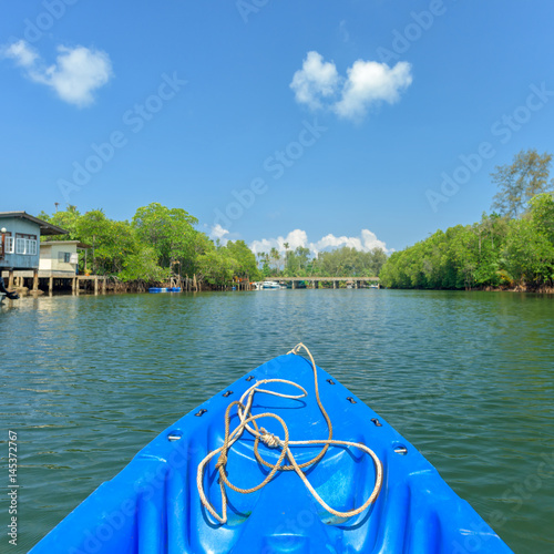 nose of canoe floating behind rower on a river © yotrakbutda