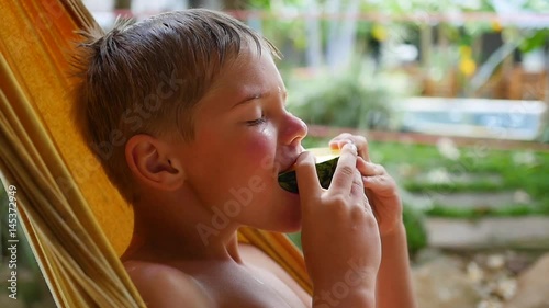 The child is eating sweet juicy watermelon on a hot summer day lying on a hammock