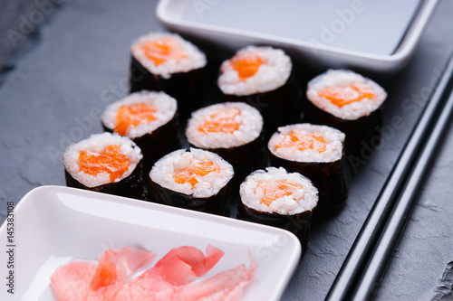 Sushi rolls with salmon, chopsticks and dishes with soy sauce and ginger 