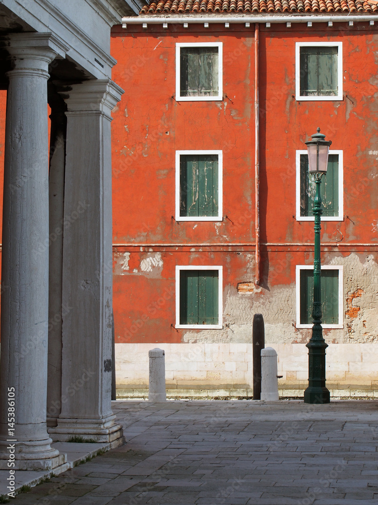 Old building in Venice with faded red wall and green shutters Old building in Venice with faded red wall and green shutters