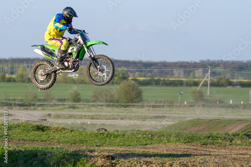 Motocross driver in action accelerating the motorbike on muddy race track.