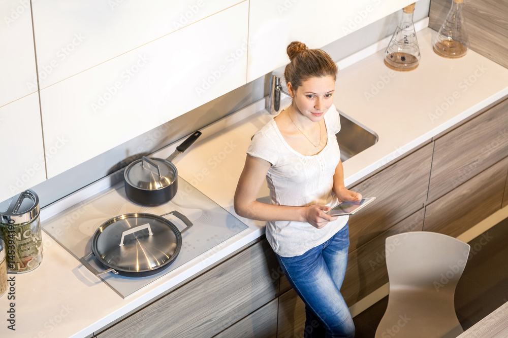 Beautiful young woman using a digital tablet in the kitchen. Beautiful young woman using a digital tablet in the kitchen.