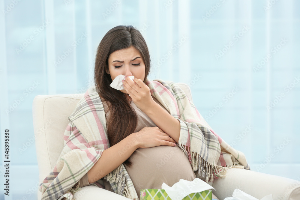 Pregnant woman with allergy sitting on armchair at home Pregnant woman with allergy sitting on armchair at home