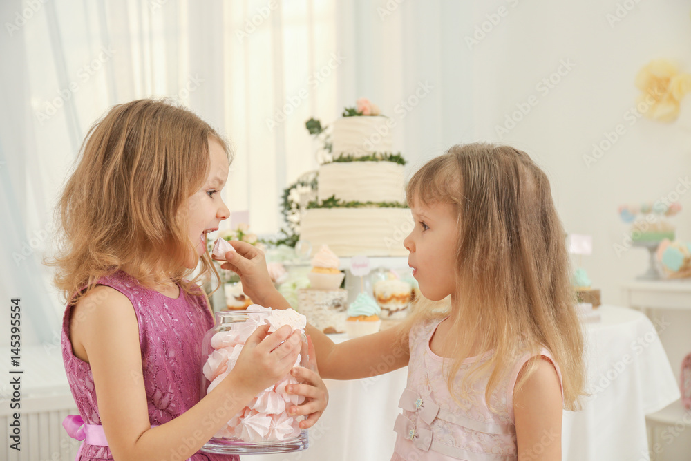 Cute little girls eating tasty sweets at party