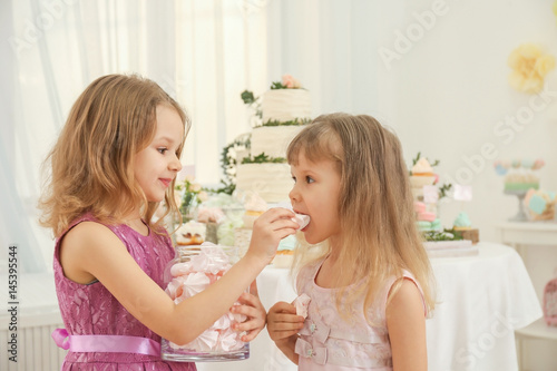 Cute little girls eating tasty sweets at party