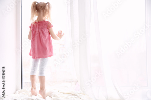 Принти на полотні Cute little girl standing on windowsill