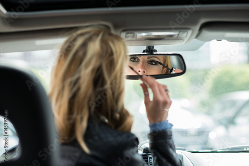 Woman applying make-up in car