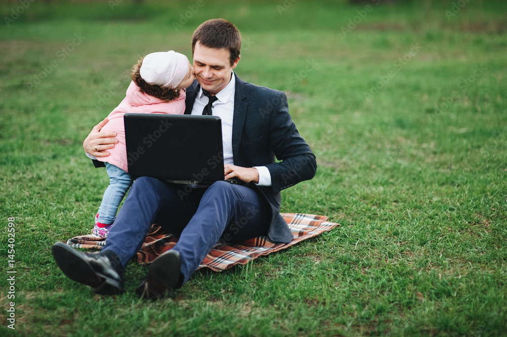 Businessman in nature with laptop on a walk with his little daughter.