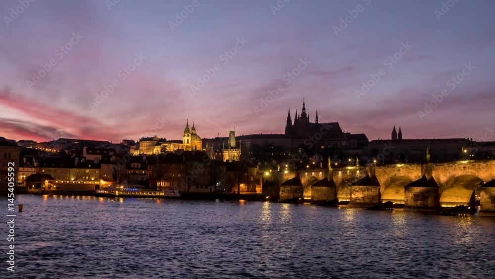 Splendid view on the Charles Bridge with anamazing dark red and grey skyscape. streaming ships, sparkling waters of the Vltava river n the evening twilights, taken as a timelapse and zoom out shot Splendid view on the Charles Bridge with anamazing dark red and grey skyscape. streaming ships, sparkling waters of the Vltava river n the evening twilights, taken as a timelapse and zoom out shot