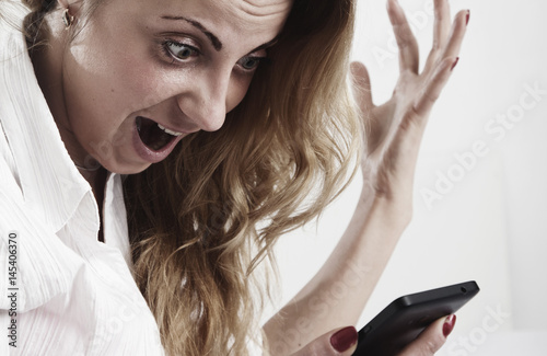 Desperate young businesswoman holding smartphone and shouting