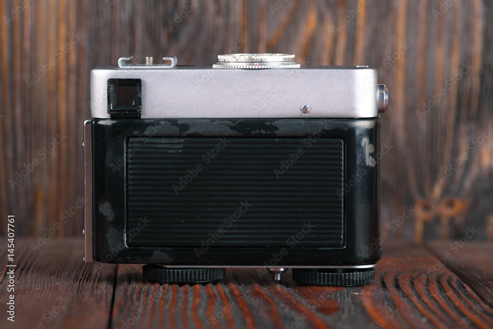 Fototapeta premium The old rangefinder camera on a wooden background.