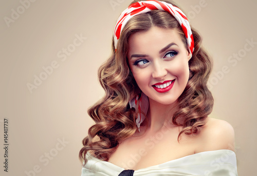 Beautiful retro vintage pin-up girl . Beautiful girl with curly hair pointing to the side . Presenting your product. Expressive facial expressions