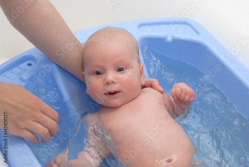 Mother washing a newborn baby in bathtub