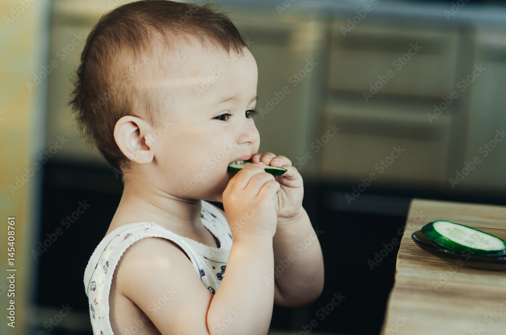 Little boy eating a fresh cucumber
