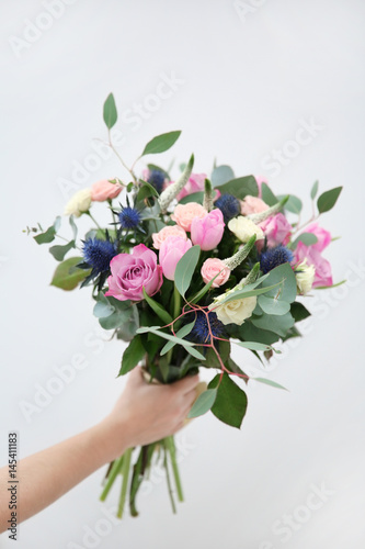 Female hand holding beautiful bouquet on light background