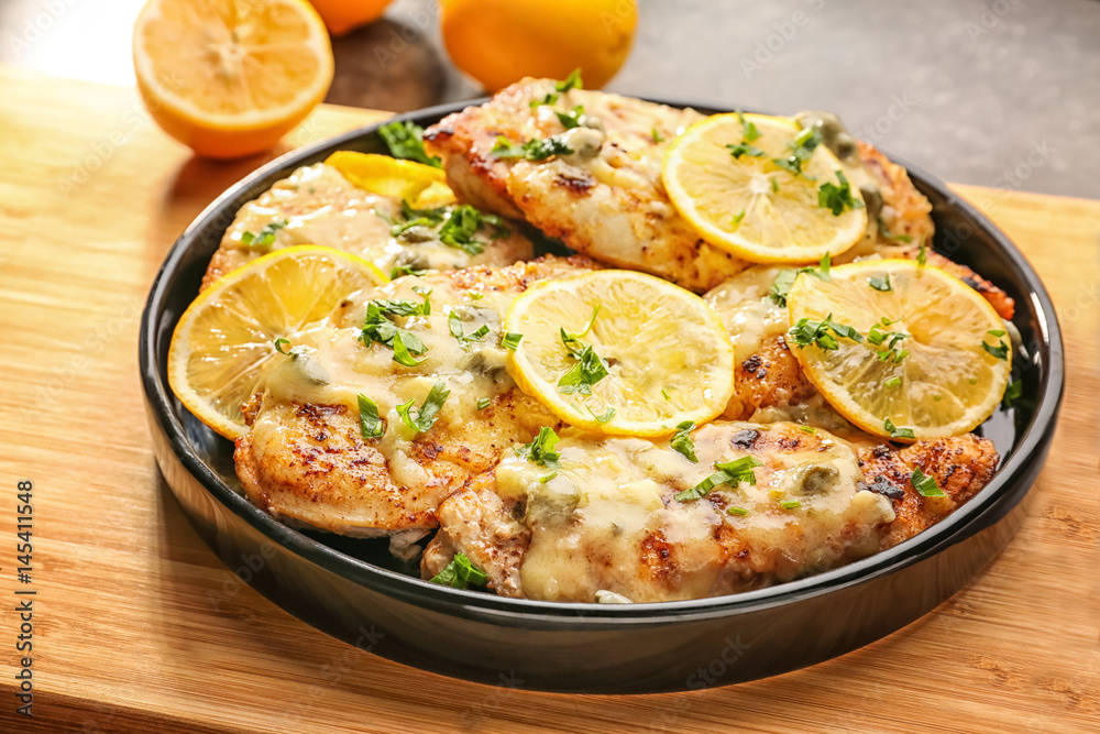 Plate with delicious chicken piccata on wooden board Plate with delicious chicken piccata on wooden board