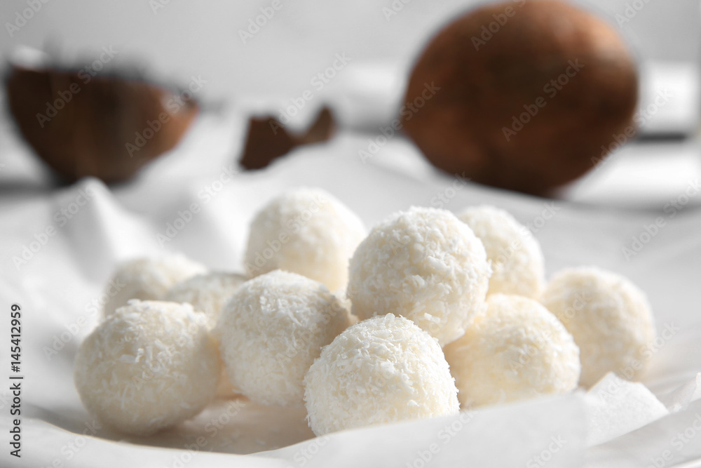 Tasty candies in coconut flakes on plate, closeup Tasty candies in coconut flakes on plate, closeup