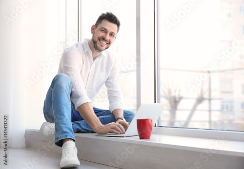 Handsome young man with lap...