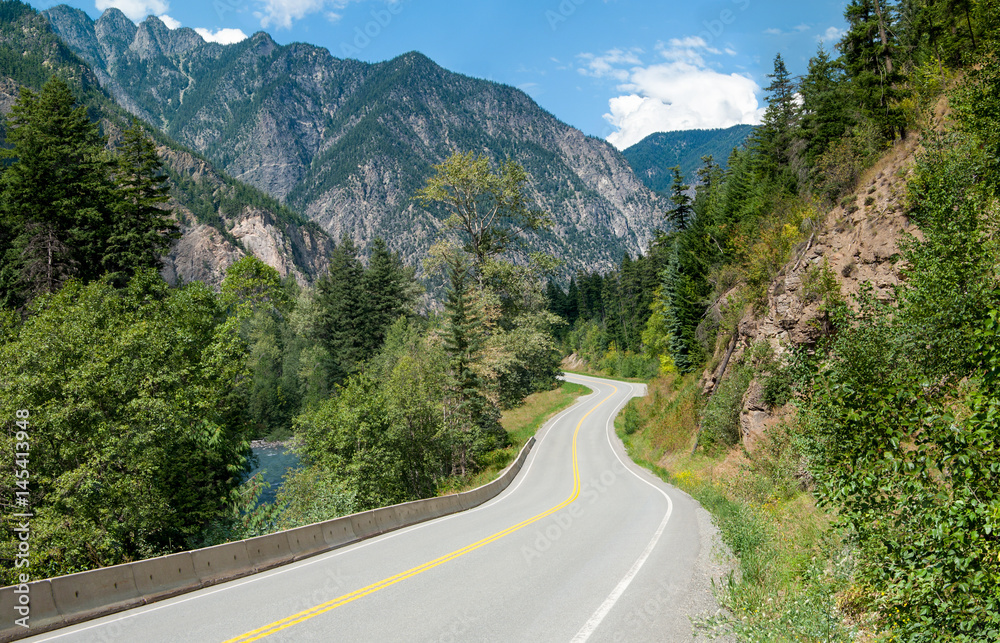 Scenic Road in British Columbia:  A winding tree-lined road passes a stream and rocky outcroppings in its climb through the mountains northeast of Vancouver, Canada.
