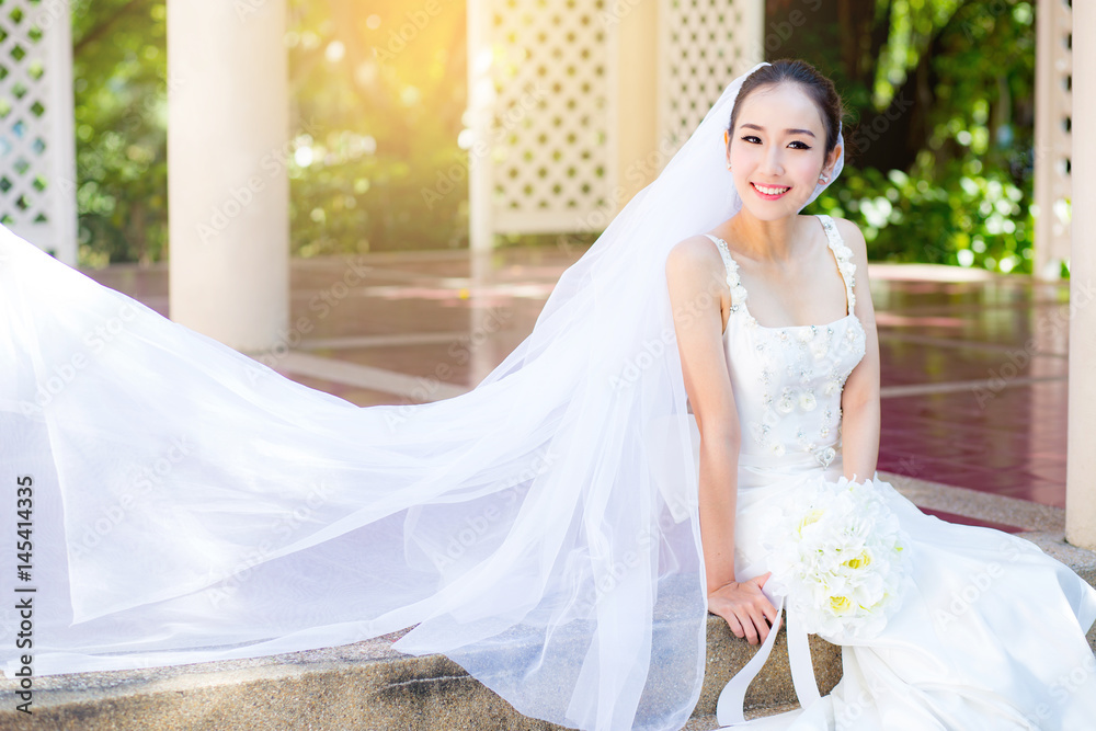 bride is sitting with flowers. Beautiful Young woman posing in park or garden in white bridal dress outdoors on a bright sunny day. bride is sitting with flowers. Beautiful Young woman posing in park or garden in white bridal dress outdoors on a bright sunny day.