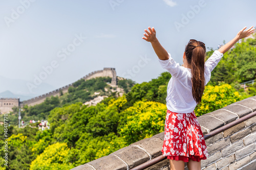 Carefree woman tourist with arms up on Great Wall of china having fun at famous Badaling attraction during travel vacation in Beijing. Winning, success, freedom trousim concept. photo
