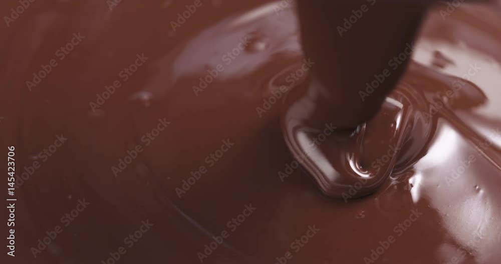 Slow motion of premium dark melted chocolate being poured from spoon in right part of frame, 4k 60fps prores footage Slow motion of premium dark melted chocolate being poured from spoon in right part of frame, 4k 60fps prores footage