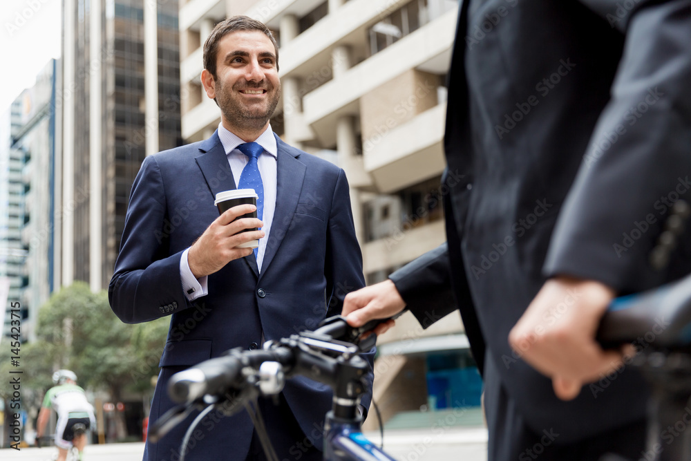 Two young businessmen with a bike in city centre